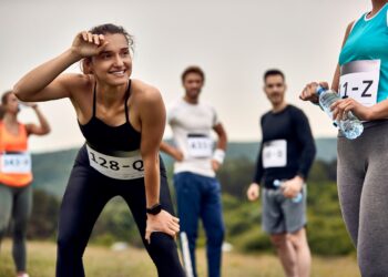 Happy sportswoman feeling exhausted after running a marathon in nature.