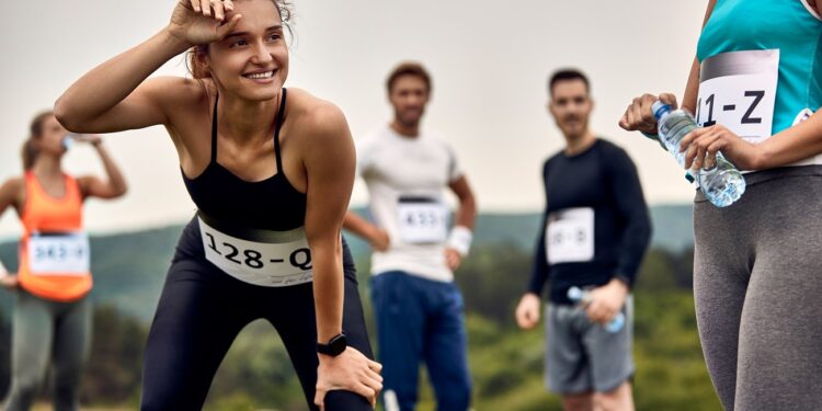 Happy sportswoman feeling exhausted after running a marathon in nature.