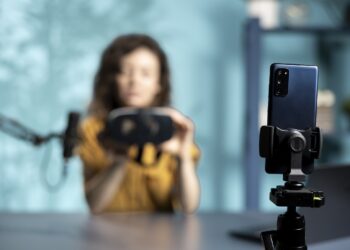 Focus on smartphone used by tech vlogger to review VR glasses in studio. Close up of phone used by woman filming virtual reality headset presentation vlog for technology enthusiasts