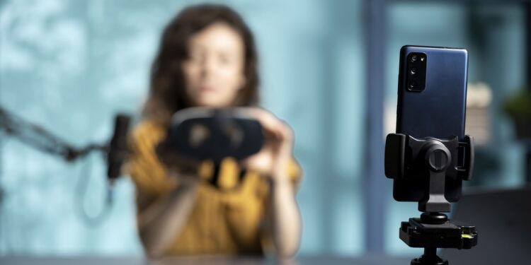 Focus on smartphone used by tech vlogger to review VR glasses in studio. Close up of phone used by woman filming virtual reality headset presentation vlog for technology enthusiasts
