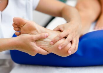Medical massage at the foot in a physiotherapy center. Female physiotherapist inspecting her patient.