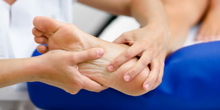 Medical massage at the foot in a physiotherapy center. Female physiotherapist inspecting her patient.