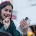 Stylish young woman on a walk in the city holding a smartphone in her hands, Christmas stylish look.