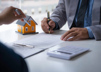 Discussion with a real estate agent, House model with agent and customer discussing for the contract to buy, get insurance or loan real estate or property.