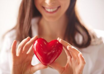 Close-up of smiling female holding red heart
