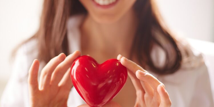 Close-up of smiling female holding red heart