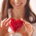 Close-up of smiling female holding red heart