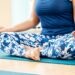 Attractive young woman exercising and sitting in yoga Lotus pose with mudra gesture position while resting at home, Concept of healthy life and natural balance between body and mental development