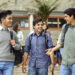 Smiling young men talking while walking in campus. Happy male students are listening to friend. They are in casuals.