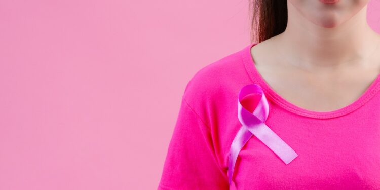 Breast cancer awareness month, Woman in pink t-shirt with satin pink ribbon on her chest, supporting symbol of breast cancer awareness campaign in October.