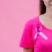 Breast cancer awareness month, Woman in pink t-shirt with satin pink ribbon on her chest, supporting symbol of breast cancer awareness campaign in October.