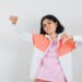 Teen girl in jacket,pink shirt showing thumb down,her fist and looking displeased , front view.