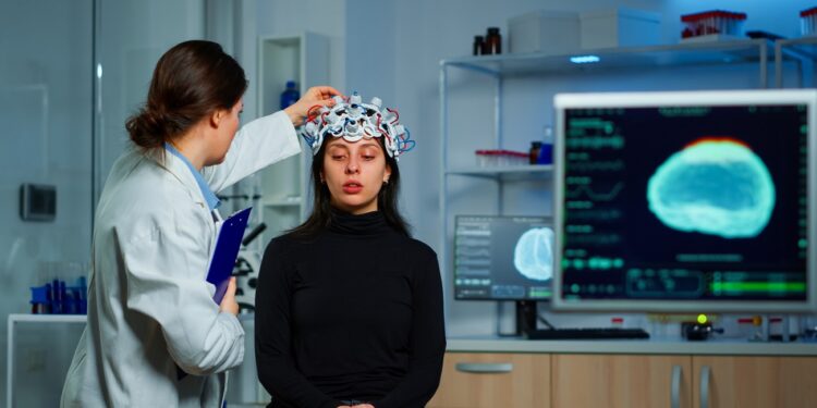 Neurological doctor cheking eeg headset explaining to patient diagnosis of disease and treatment for nervous system. Scientist researcher analysing brain scan and tomography on monitor in lab