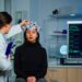 Neurological doctor cheking eeg headset explaining to patient diagnosis of disease and treatment for nervous system. Scientist researcher analysing brain scan and tomography on monitor in lab