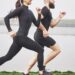 Couple jogging and running outdoors in park near the water. Young bearded man and woman exercising together in morning.