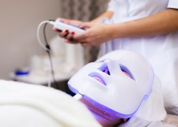 The client lies in the salon on the cosmetology table with a white mask on her face
