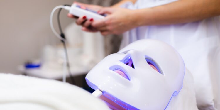 The client lies in the salon on the cosmetology table with a white mask on her face