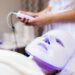 The client lies in the salon on the cosmetology table with a white mask on her face