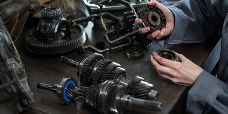 female mechanic holding spare parts of car