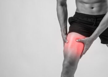 young sport man with strong athletic legs holding knee with his