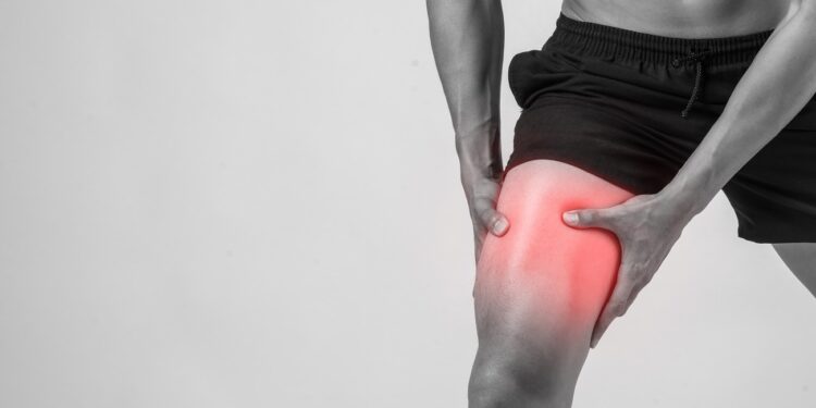 young sport man with strong athletic legs holding knee with his
