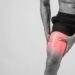 young sport man with strong athletic legs holding knee with his
