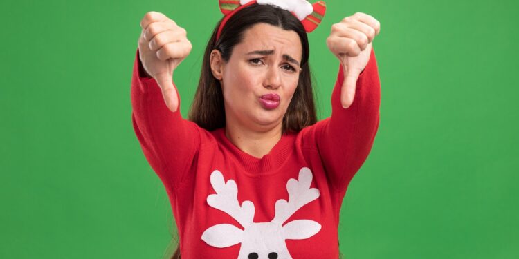 unpleased young beautiful girl wearing christmas sweater with christmas hair hoop showing thumbs down isolated on green background