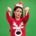 unpleased young beautiful girl wearing christmas sweater with christmas hair hoop showing thumbs down isolated on green background