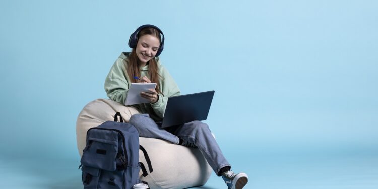student wearing headphones and holding notebook, practicing before exam