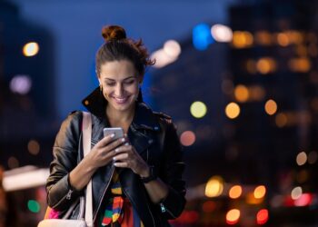 young woman with smartphone at night in a urban city area