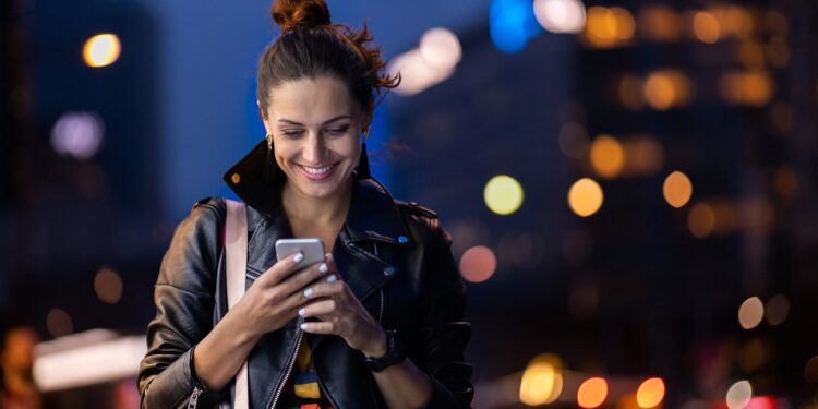 young woman with smartphone at night in a urban city area
