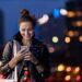 young woman with smartphone at night in a urban city area