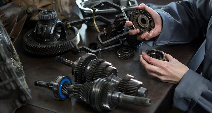 female mechanic holding spare parts of car