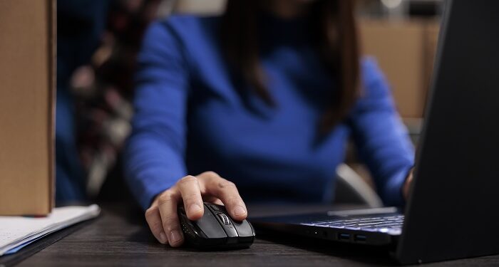 woman managing parcel delivery on laptop in warehouse
