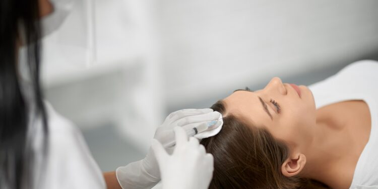 beautician in protective mask doing procedure for hair.