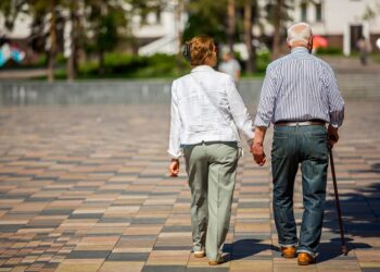 senior adults walking in a park holding hands