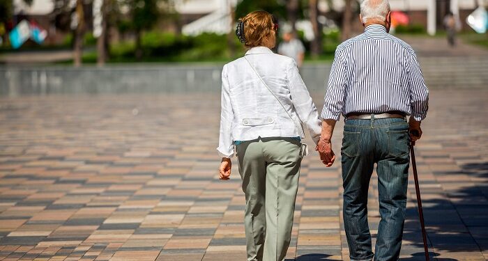 senior adults walking in a park holding hands
