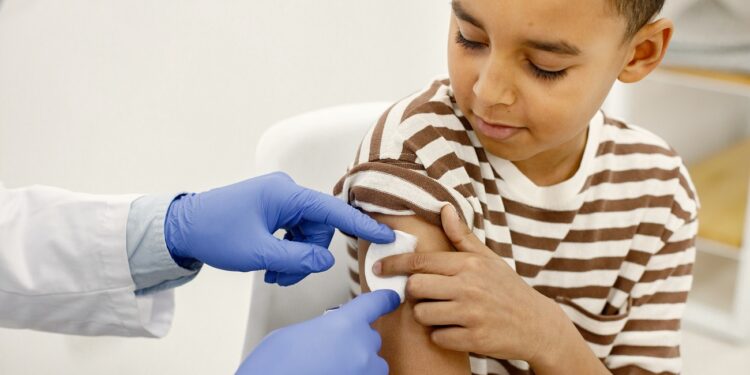 male doctor holding a cotton on a boy's shoulders after a vaccin