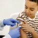 male doctor holding a cotton on a boy's shoulders after a vaccin