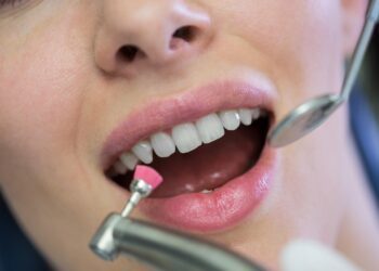 dentist examining a female patient with tools at dental clinic