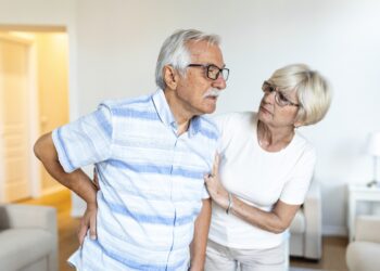 senior couple at home.elderly man is having back pain and his lovley wife supports him.