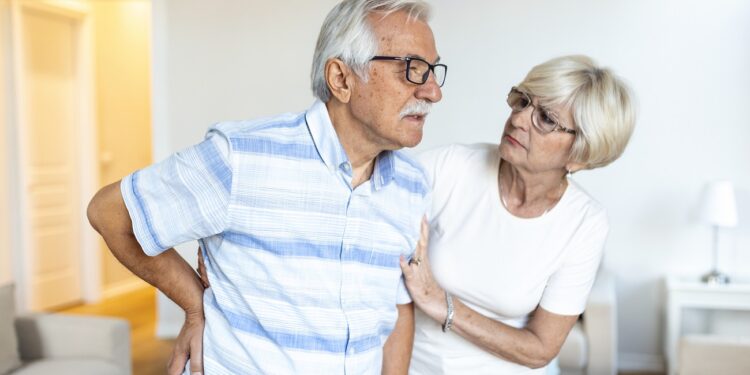 senior couple at home.elderly man is having back pain and his lovley wife supports him.