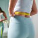 young woman taking measurements of her body in front of the mirr