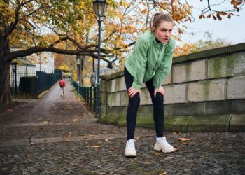 tired sporty girl resting after run in beautiful autumn city park