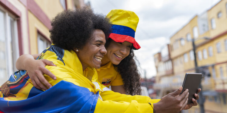 afro latin couple is outside their house watching the soccer game through their tablet