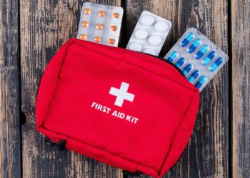 first aid kit with pills top view on a dark wooden background
