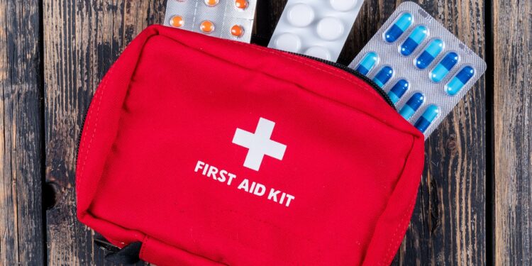 first aid kit with pills top view on a dark wooden background