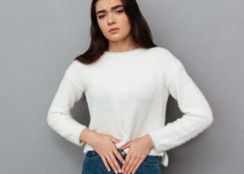 close up photo of depressed young woman with abdominal pain, loo