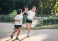two young adult woman running in a park.