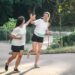 two young adult woman running in a park.